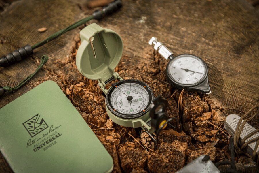 Helikon-Tex® Ranger MK2 compass and a rugged notebook on a tree stump, ready for outdoor navigation. Photo: Helikon-Tex, Rigad.