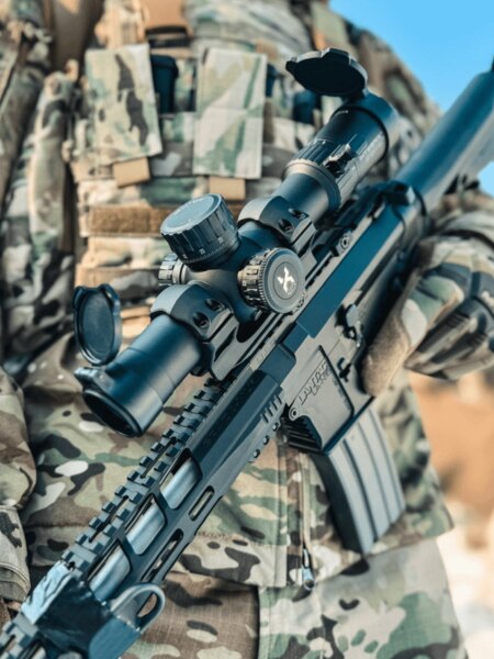 Close-up of a Vortex Optics riflescope mounted on a modern assault rifle with a Picatinny rail, shooter in camouflage. Photo: Rigad