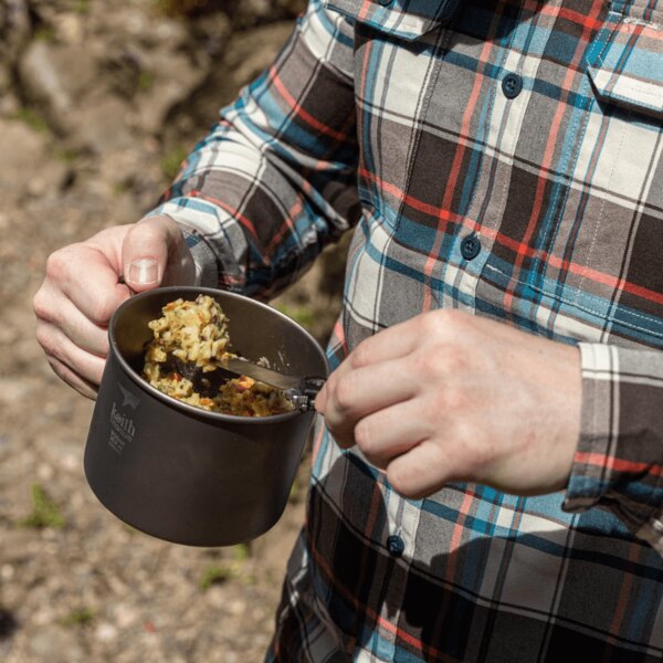Keith titanium mug with food held in hand during an outdoor adventure. Photo by Rigad.