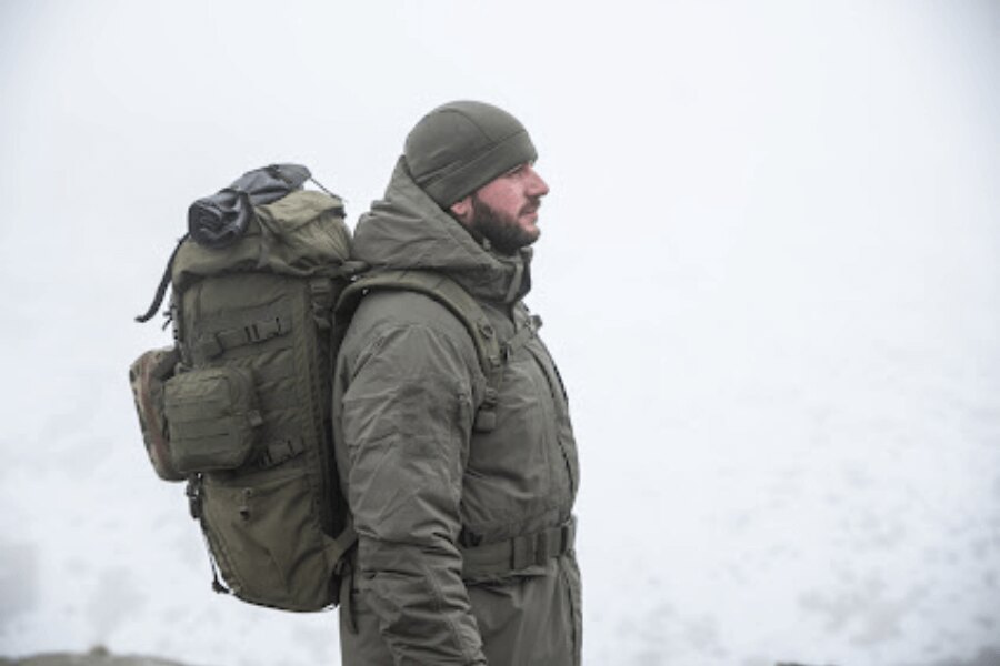 Movement in the field under adverse weather conditions, with a backpack and layered clothing, illustrating pace management in cold and rainy terrain. Photo: Rigad