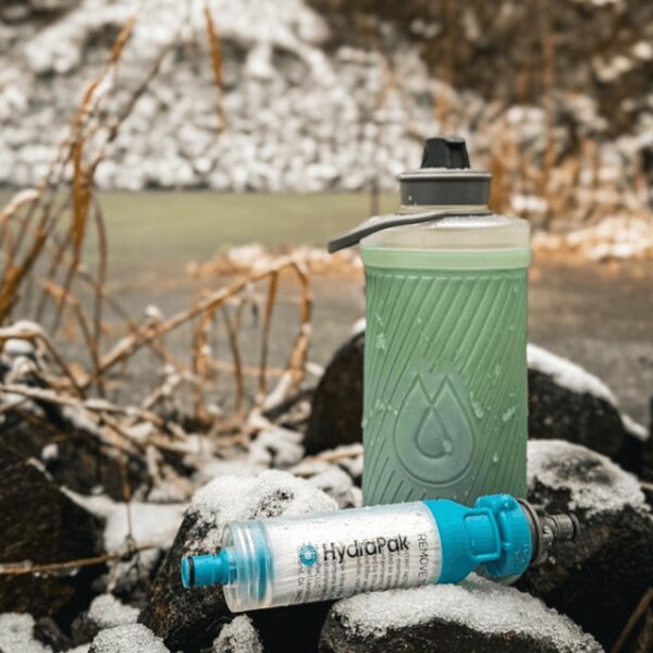Hydrapak bottle and water filter lying on the snow. Outdoor hydration system in a winter environment. Photo: Rigad