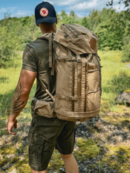 Man with backpack and Fjällräven cap on a summer hike – sunstroke prevention. Photo: Rigad.