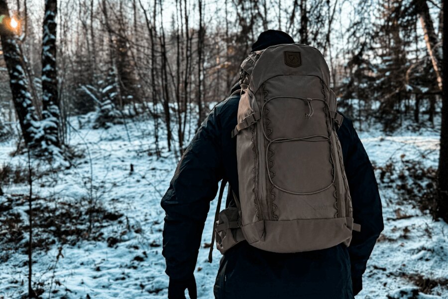 Man with a large backpack is walking through a winter forest. Photo: Rigad