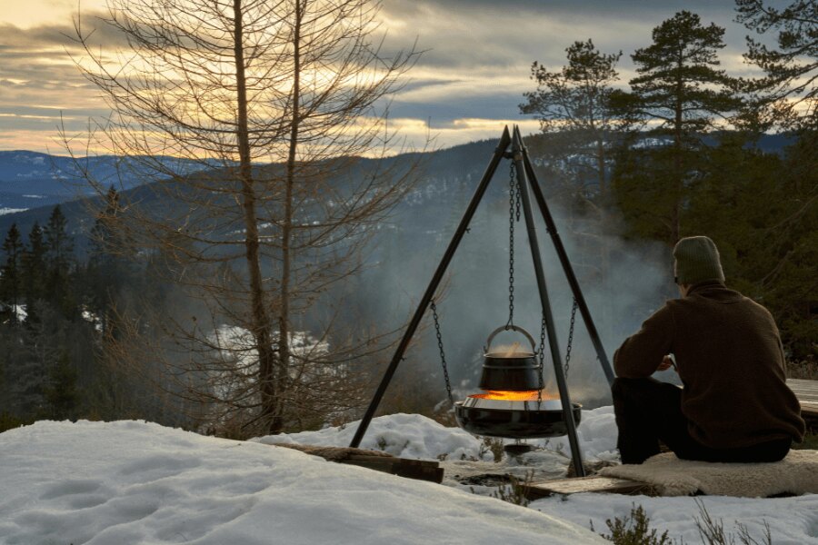 A man camping in snowy nature. Source: https://www.pexels.com/cs-cz/foto/zimni-vareni-u-taboraku-v-norskem-lese-31189383/