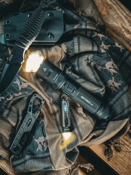 NexTorch® P84 tactical flashlight carried on gear alongside an ANV knife and everyday carry equipment. Photo: Rigad