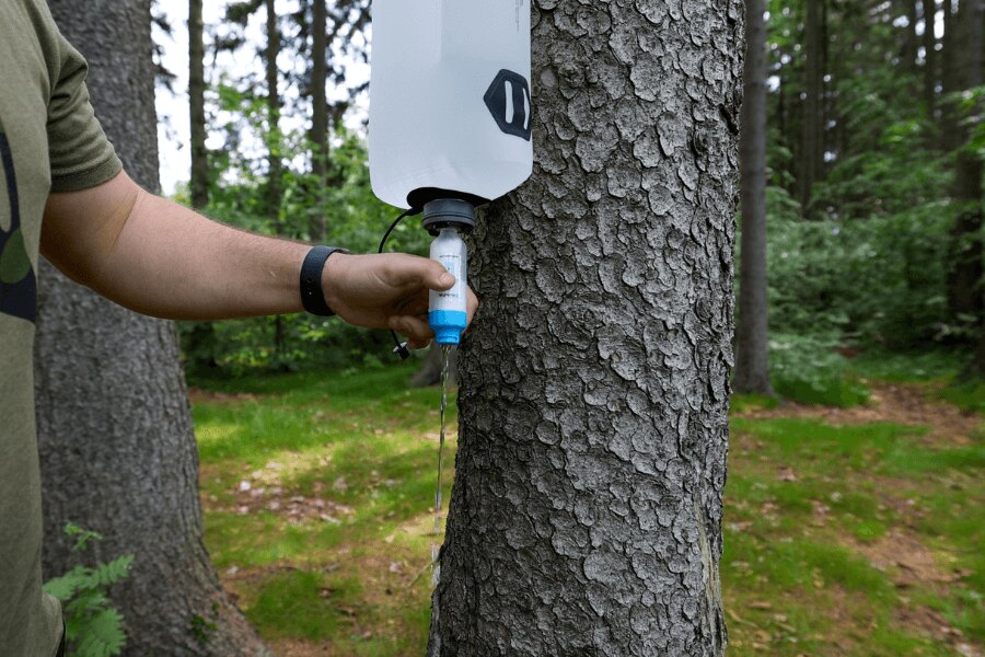 Gravity water filter hanging from a tree during outdoor water filtration. Photo: Rigad