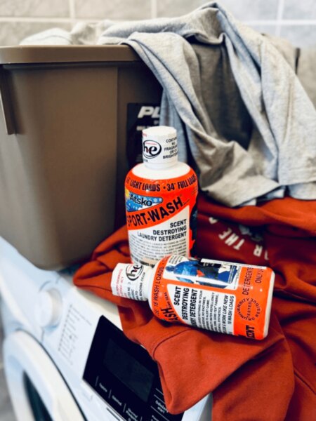Atsko Sport-Wash detergents with clothing and a Plano storage box on top of a washing machine.
