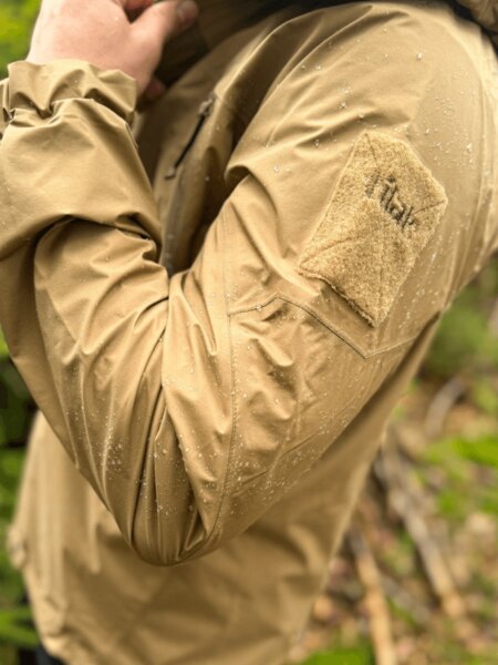 Stinger Gore-Tex<sup>®</sup> Paclite Plus<sup>®</sup> Tilak Military Gear<sup>®</sup> Jacket – detail of the waterproof hardshell with taped seams and VELCRO panel on the sleeve in the rain. Photo: Rigad