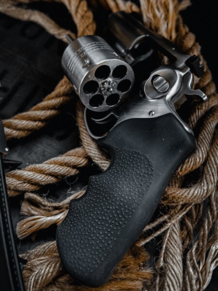 Close-up of a modern revolver with the empty cylinder swung open and a black rubber grip.
