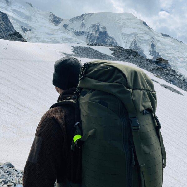 Trekker with a large tactical backpack crossing glacial terrain in the mountains. Source: Rigad