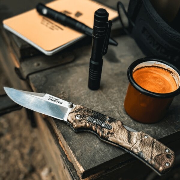 Knife, flashlight, notebook, and mug on a table — essential gear for everyday preparedness. Photo: Rigad