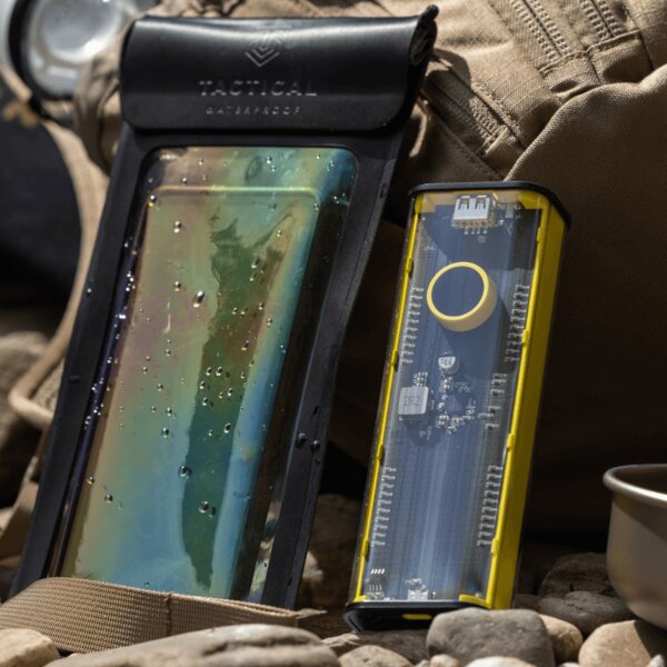 Power bank and waterproof phone pouch placed on rocks next to a backpack. Photo: Rigad