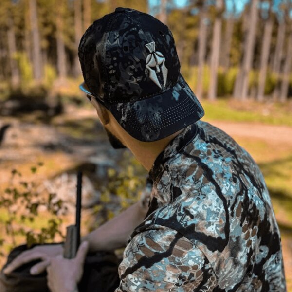 Rear view of a man wearing a Kryptek Altitude cap in a forest setting. Photo by Rigad.