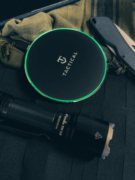 Tactical<sup>&reg;</sup> Base Plug Wireless Charger with illuminated LED ring placed on tactical gear – Qi 15 W, non-slip surface. Photo: Rigad.