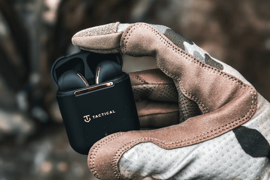 Tactical<sup>&reg;</sup> Black Hawk StrikePods earbuds in an open charging case, held in tactical gloves – wireless TWS with ENC and rugged design. Photo: Rigad.