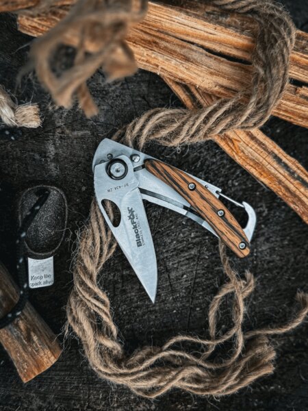 Black Fox® folding knife with a wooden handle cutting rope in an outdoor environment. Photo: Rigad
