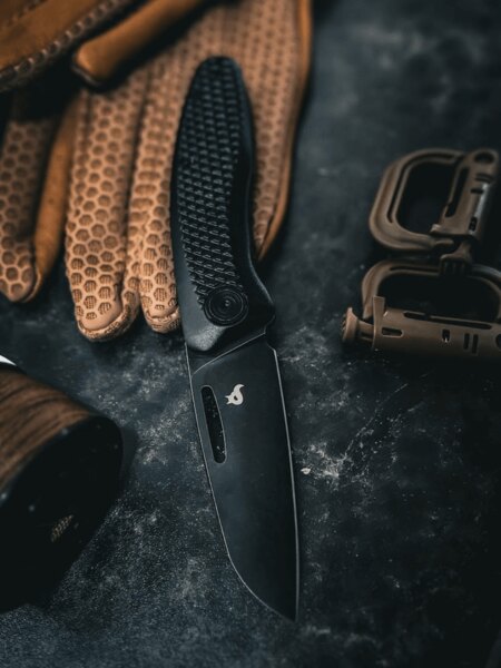 Modern closing knife Black Fox® with a black blade placed on work gloves. Photo: Rigad