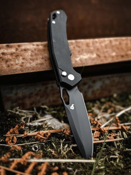 Black Fox® folding knife with a black blade and G10 handle in an outdoor setting. Photo: Rigad