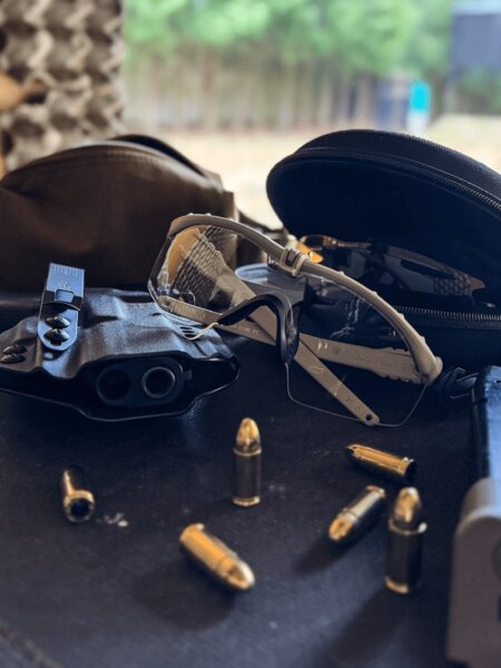 Shooting glasses with clear lenses on the shooting range table next to ammunition and accessories; suitable for training and courses. Photo: Rigad