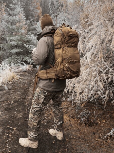 Winter movement under the horizon — tightened backpack without flapping, broken lines on pants; brown-gray works among conifers and deciduous trees. Photo: Rigad