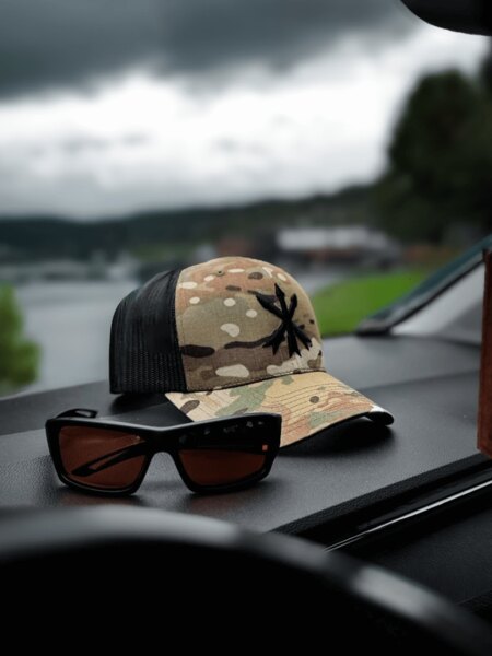 Multicam trucker cap with the Unity Tactical logo and shooting protective glasses on the dashboard. Photo: Rigad