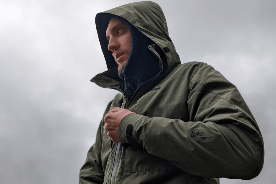 Tilak Loke 24 from Ventile<sup>&reg;</sup> in olive, hood on, fastening with waterproof zipper; silent, breathable rain protection. Photo: Rigad