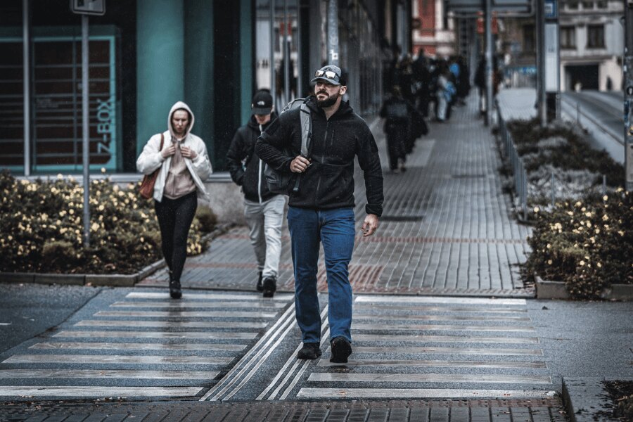 Man in a black Helikon-Tex Patriot Pro hoodie walking in the city - technical hoodie in a civilian style for everyday wear. Photo: Rigad