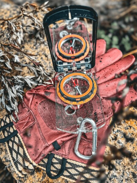 Compass and gloves placed in the field – navigation in nature without GPS using a compass. Photo: Rigad