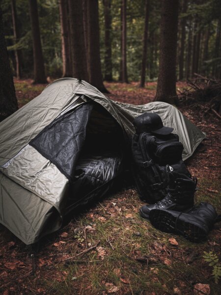 Bivouac bag Snugpak with a spread-out sleeping bag, next to it a backpack and winter boots, ready for emergency overnight stay in nature. Photo: Rigad