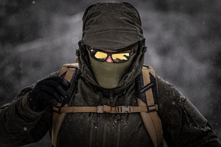 Tourist in a winter blizzard in a durable insulated Helikon-Tex Yukon jacket with a balaclava and goggles during a challenging winter ascent. Photo: Rigad