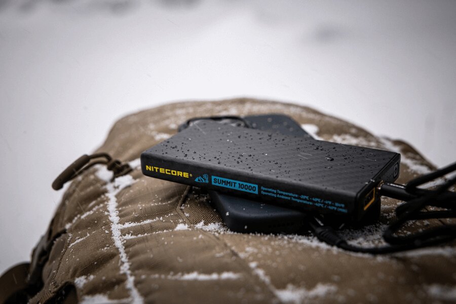 Power bank Nitecore in winter conditions placed on a backpack, covered with snow. (Photo: Rigad)