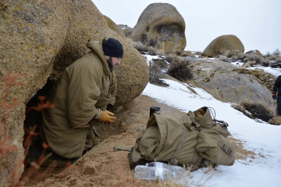 Emergency winter bivouac in the field – using a boulder as a natural windbreak against wind and cold. Photo: Helikon-Tex, Rigad