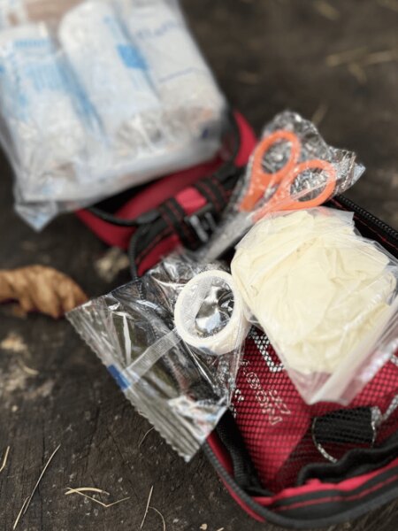 Open field first aid kit with protective gloves, scissors, and basic medical equipment. Photo: Rigad