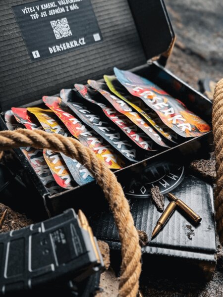 Berserkr beef jerky tasting box featuring multiple flavors, photographed alongside ammunition and field gear in an outdoor setting.