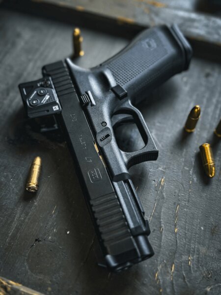 Glock 47 with an Aimpoint COA red dot mounted via the A-CUT interface, pistol detail with ammunition on the table. Photo: Rigad