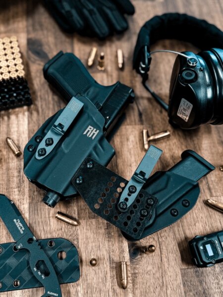 Kydex IWB Holsters with Clips and EDC Gear on a Wooden Surface