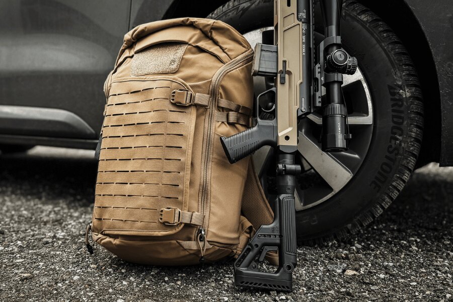 Vertx<sup>&reg;</sup> Siege Tactical Sling Backpack Leaning Against a Vehicle with a Rifle. Photo: Rigad