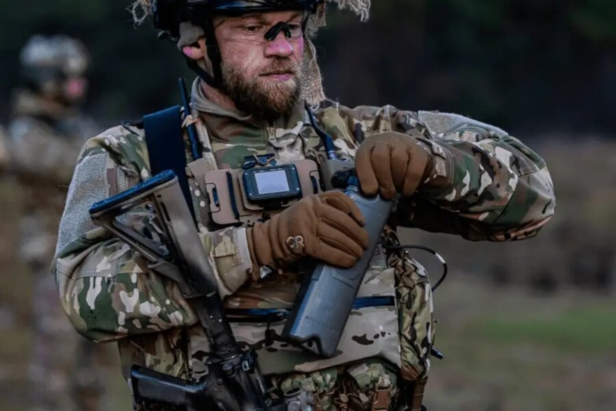 An operator in full tactical gear opens the Qore Performance ICEPLATE<sup>®</sup> hydration system during field training.