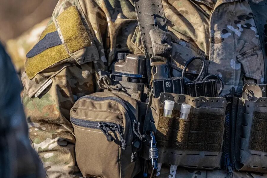 Close-up of tactical gear with a Qore Performance ICEFLASK<sup>®</sup> hydration bottle mounted inside a plate carrier.