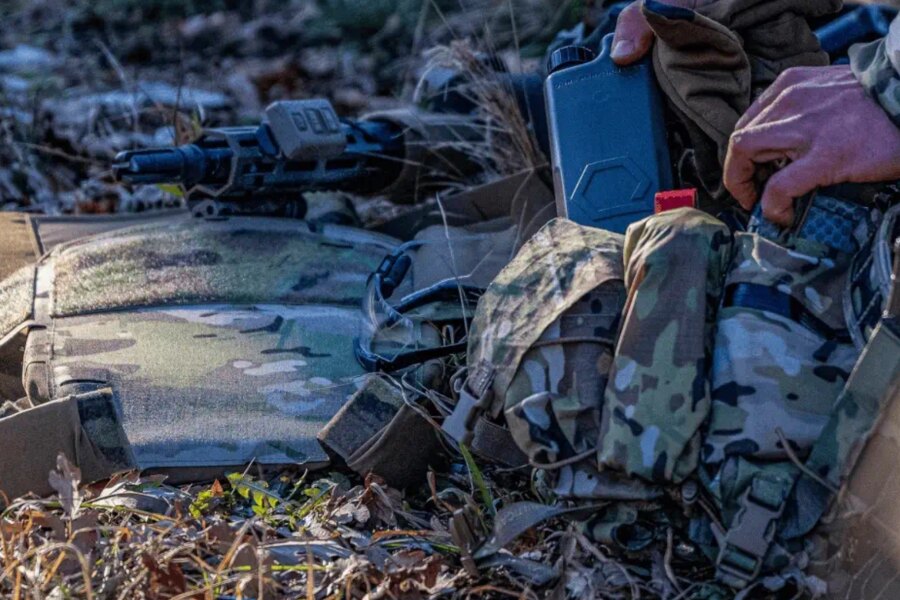 Tactical gear laid out in the field next to the Qore Performance ICEPLATE<sup>®</sup> hydration system.