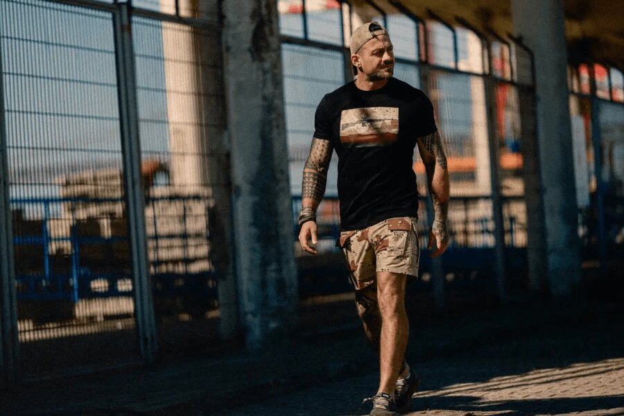 A man wearing Chocolate Chip camouflage shorts from the Helikon-Tex Retro Inspired Morale Collection.