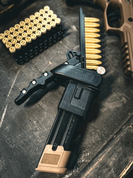 Nine Reloaded magazine loader alongside 9mm Luger cartridges and a pistol.