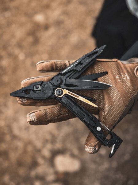 Leatherman MUT multitool held in a gloved hand during tactical use.