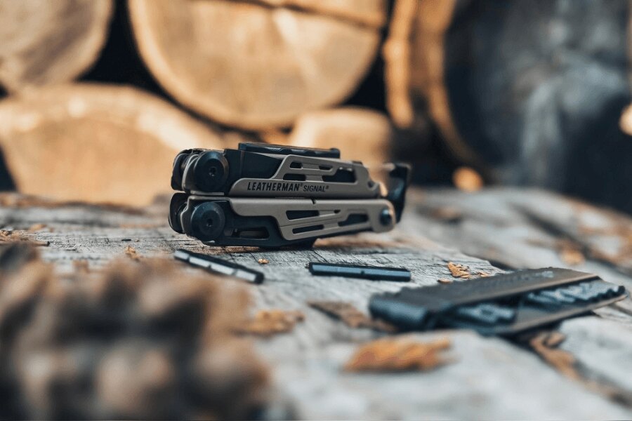 Leatherman Signal with bit kit and accessories laid out on a wooden table in an outdoor environment.