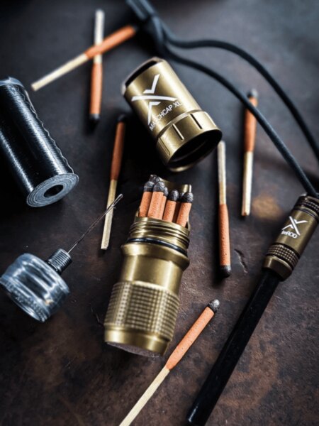Exotac MatchCap XL waterproof match container with matches and a ferro rod as part of a fire-starting kit.