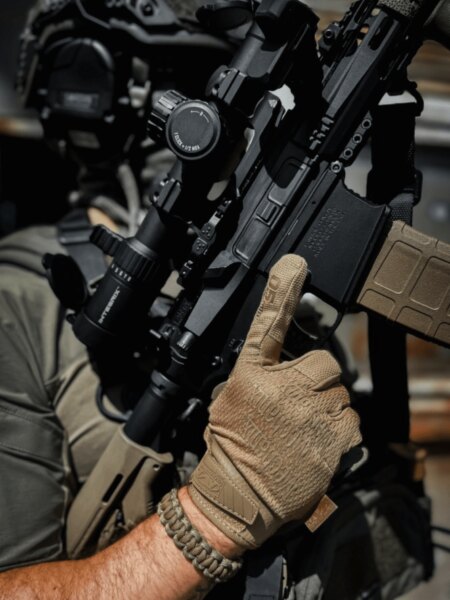 Close-up of a modern PCC equipped with an optic and magazine in the shooter's hands.
