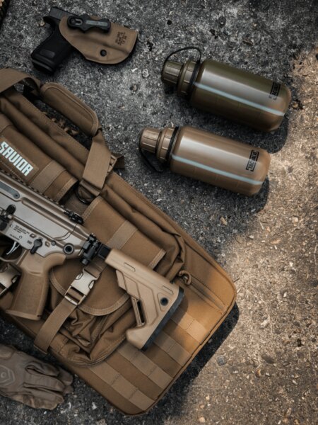 Two TacValve<sup>&reg;</sup> ModCan military canteens placed next to shooting gear and a semiautomatic rifle.
