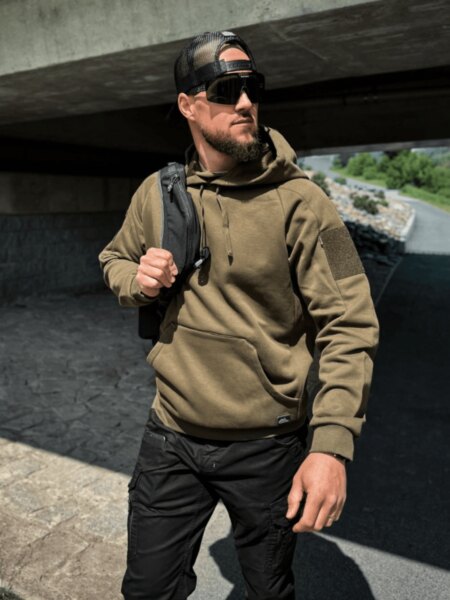 Man wearing a Helikon-Tex<sup>®</sup> Range TopCool hoodie with a range bag over his shoulder.