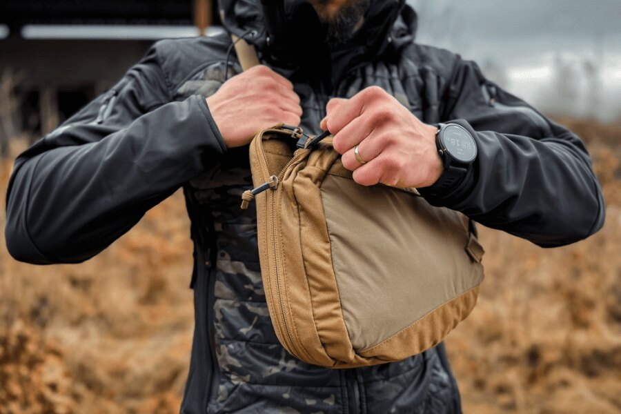 Opening the main compartment of a sling bag before drawing a handgun.