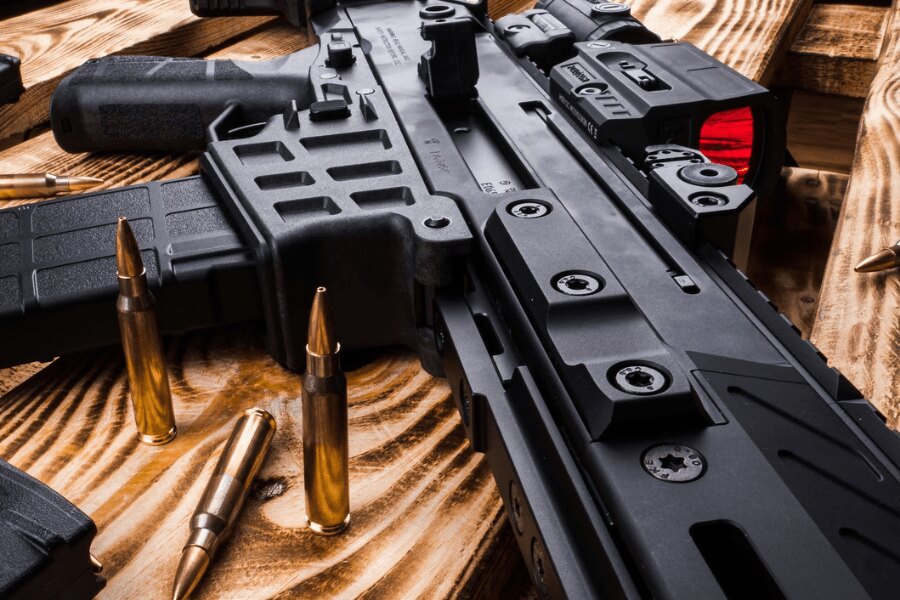 Close-up of a CZ BREN 2 semi-automatic rifle with a red dot sight on a wooden table.